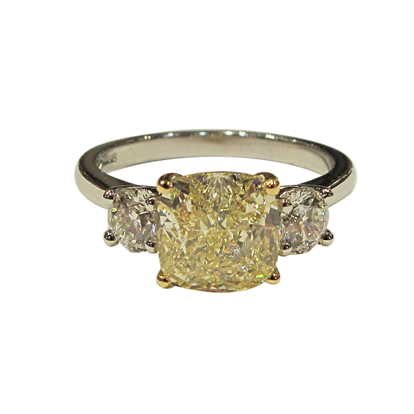 A yellow and white diamond trilogy engagement ring set in platinum band